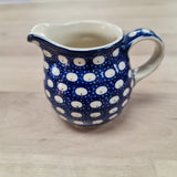 Blue pottery jug  with white  dots on a beige background