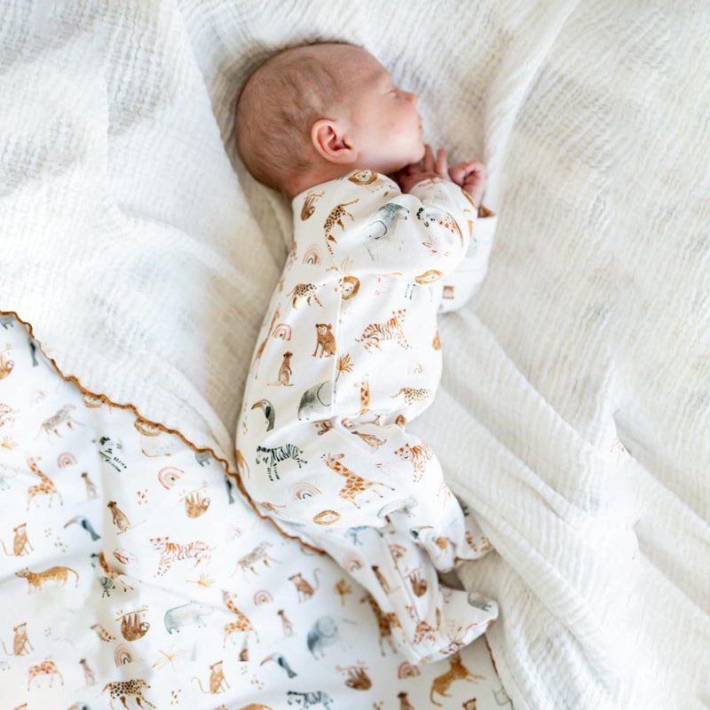 Newborn baby swaddled in a patterned blanket on a white surface