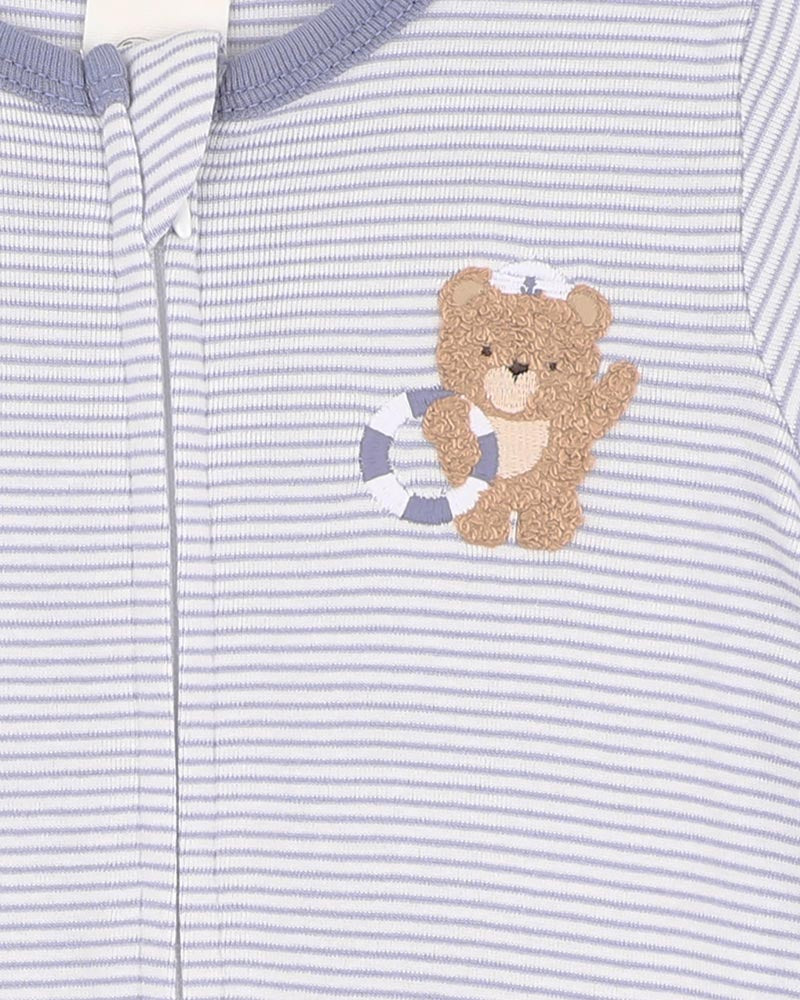 Close-up of a baby outfit with a teddy bear design on a striped background