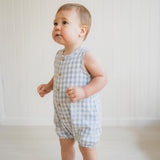 Baby wearing a blue checkered romper against a white background