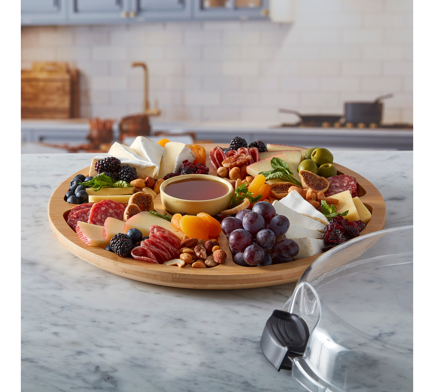 Bamboo charcuterie board with assorted meats, cheeses, fruits, and nuts on a marble countertop.