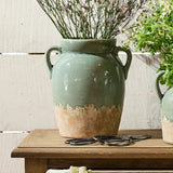 Tall pale blue and terracotta vase with handles displaying dried flowers