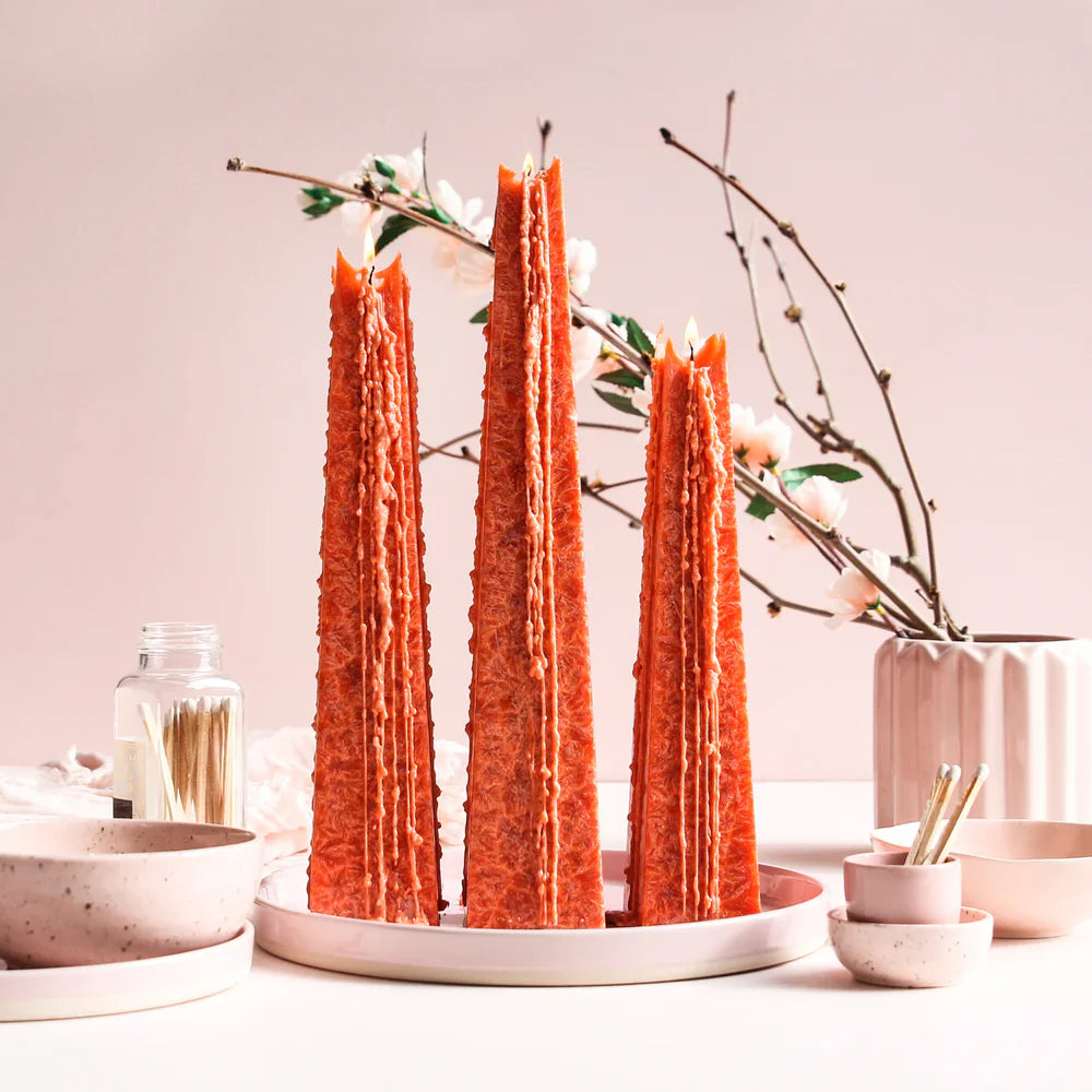Set of three orange LIving Light Icicle Candles fragranced in Guava Passion, displayed on a tray