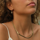 Close-up of a woman wearing gold necklaces and earrings with a blurred background
