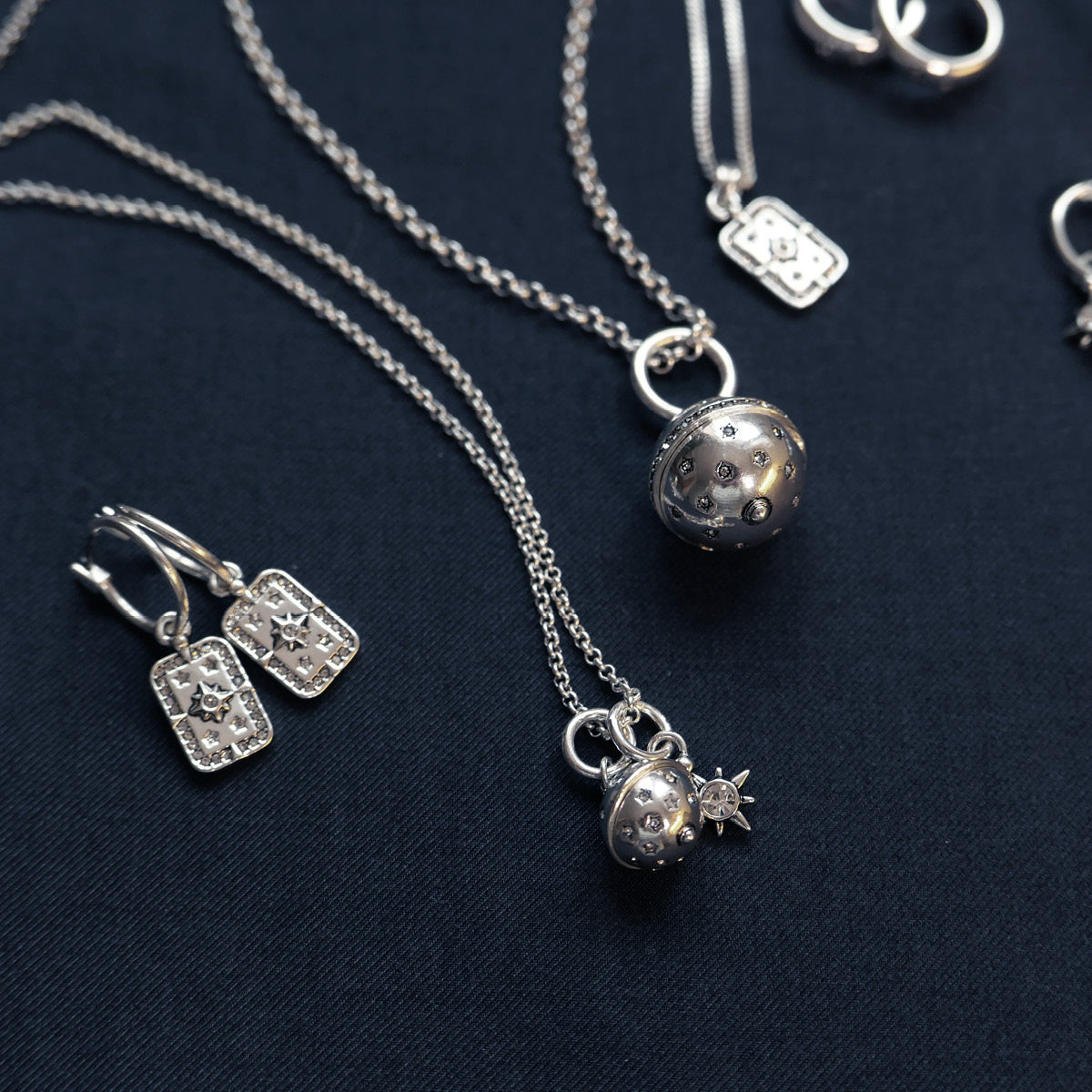 Silver jewelry set including necklaces and earrings on a dark background