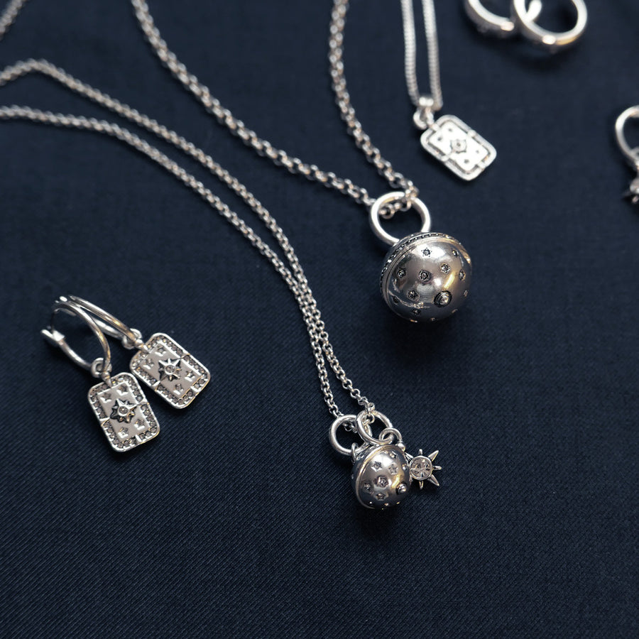 Silver jewelry set including necklaces and earrings on a dark background
