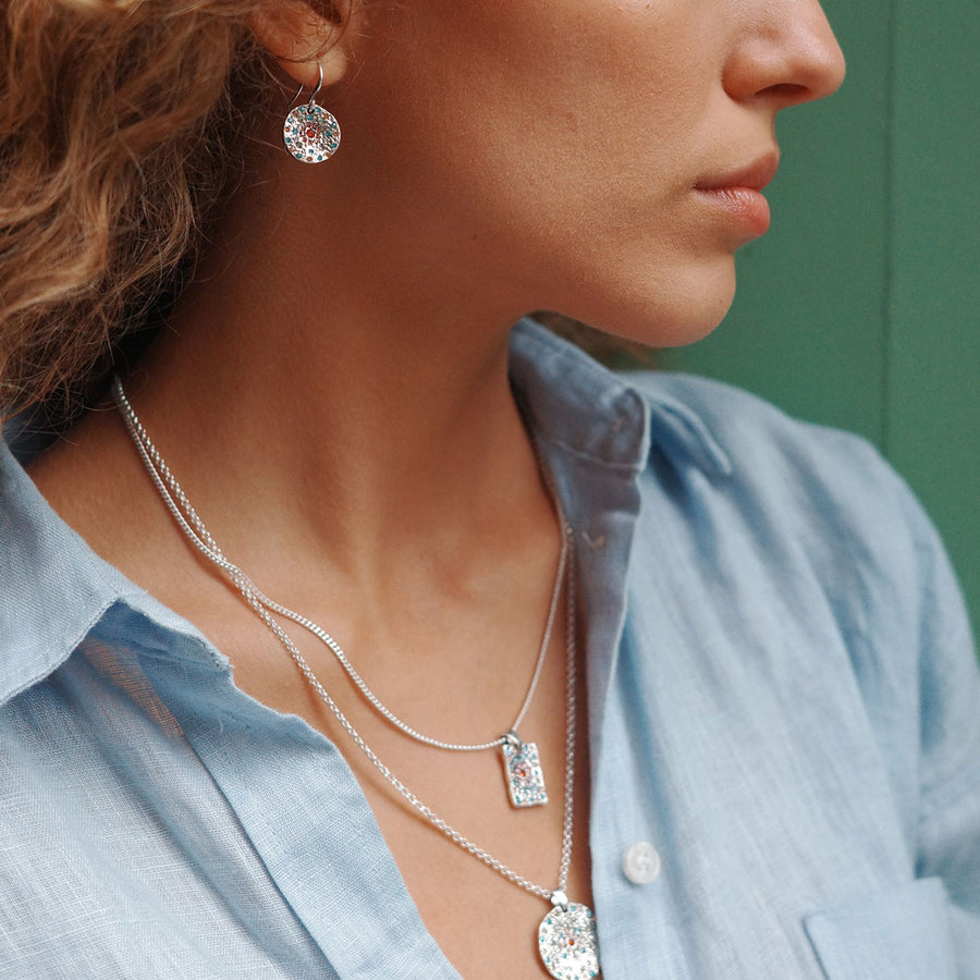 Close-up of a person wearing silver jewelry with a blurred background