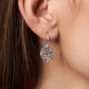 Close-up of an earring worn by a person with brown hair.