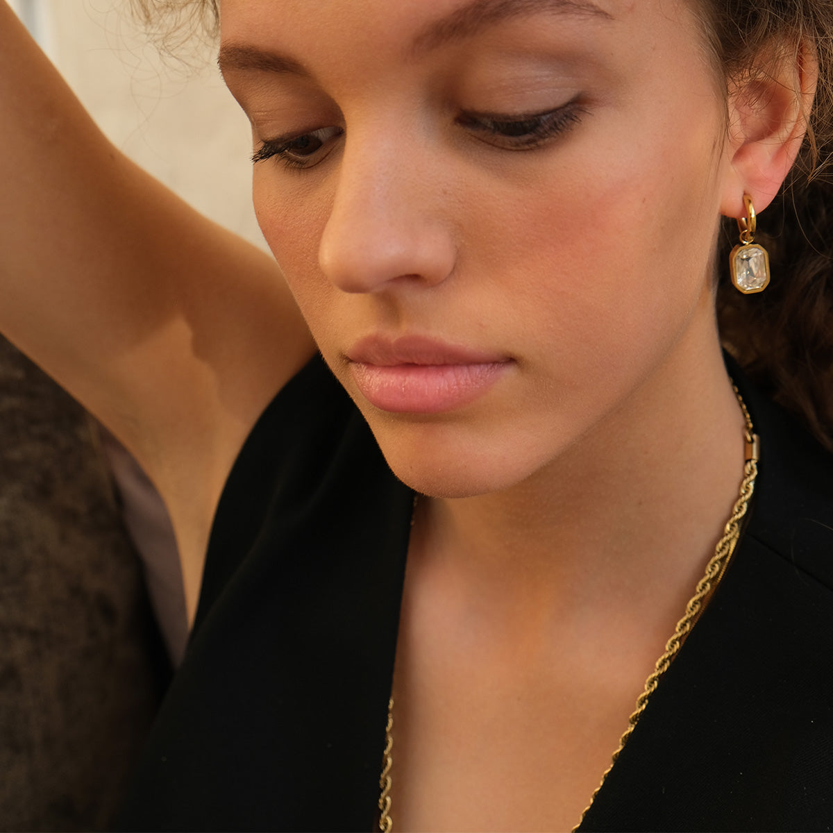Close-up of a woman wearing gold earrings and a necklace.
