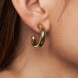 Gold hoop earring worn on an ear with a close-up view