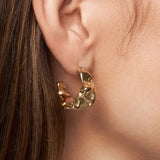 Gold hoop earring worn by a person with brown hair.