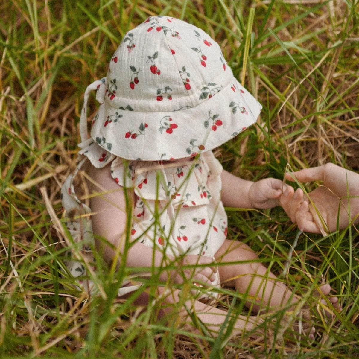 Baby wearing crinkle muslin sunhat with cherry print