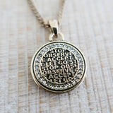 Gold pendant with engraved text on a wooden surface
