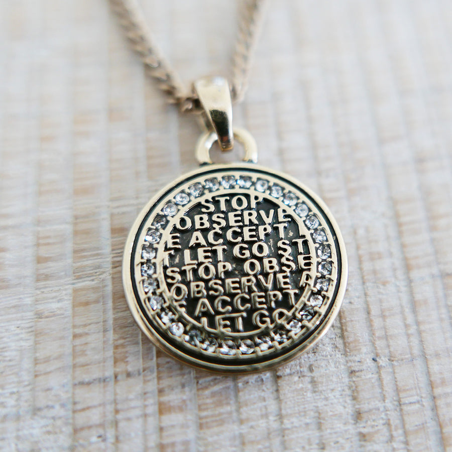 Gold pendant with engraved text on a wooden surface