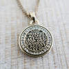 Gold pendant with engraved text on a wooden surface