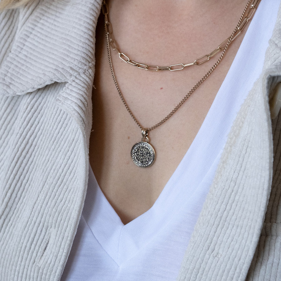 Necklace with a pendant worn by a person in a light-colored outfit