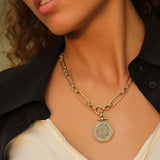 Gold chain necklace with a round pendant worn by a person