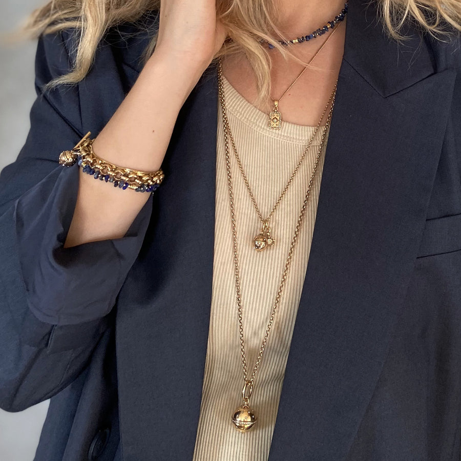 Person wearing multiple gold necklaces and a bracelet with a dark blue background