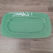 Green rectangular platter with decorative edge on a wooden floor
