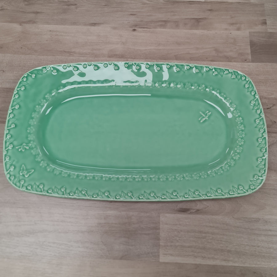 Green rectangular platter with decorative edge on a wooden floor