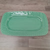 Green rectangular platter with decorative edge on a wooden floor