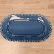 Blue oval platter with decorative edge on a wooden surface