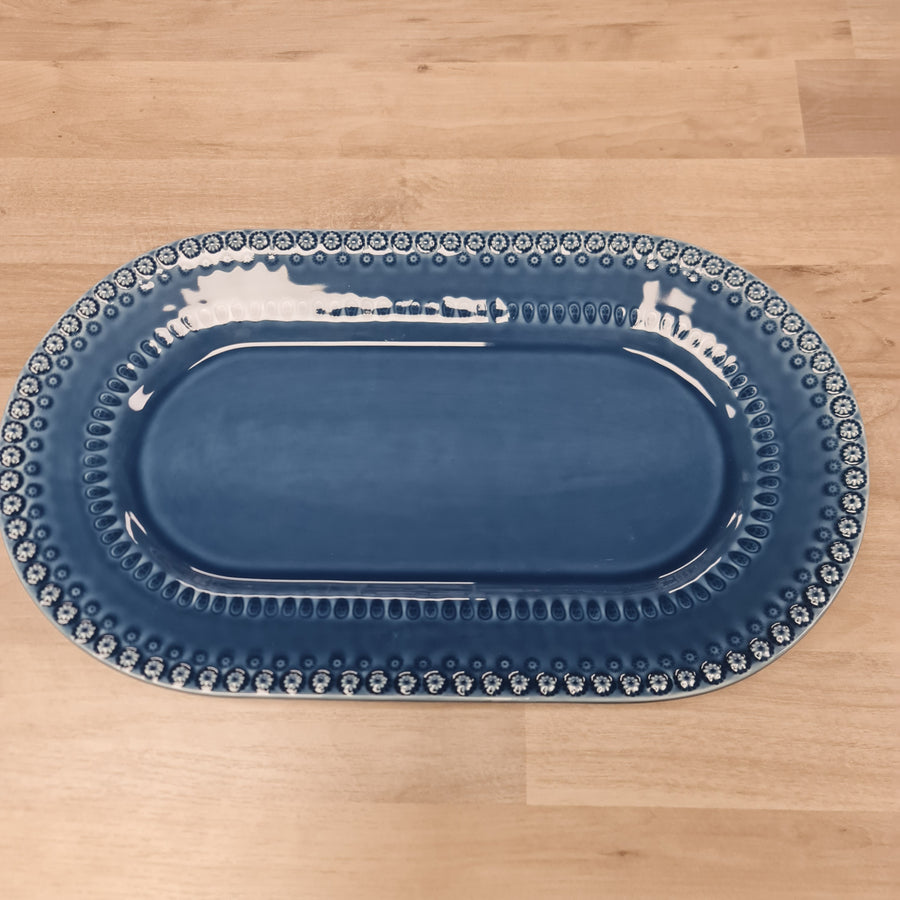 Blue oval platter with decorative edge on a wooden surface