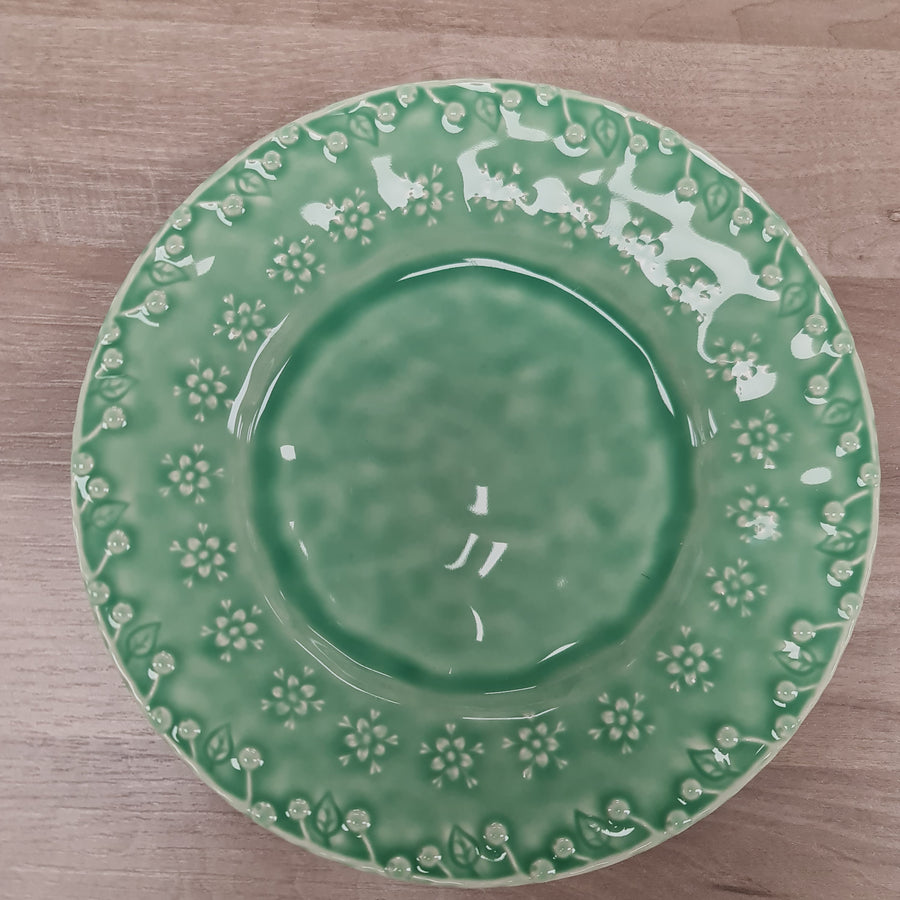 Green ceramic plate with decorative edge on a wooden surface