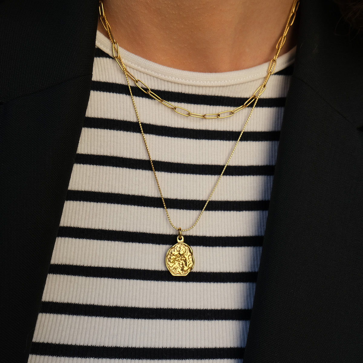 model wearing Gold necklace with 2 chains, the longer chain has a gold pendant on it, the shorter chain is a slightly chukier gold link