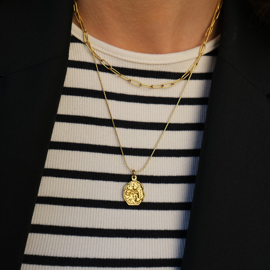model wearing Gold necklace with 2 chains, the longer chain has a gold pendant on it, the shorter chain is a slightly chukier gold link