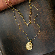 Gold necklace with 2 chains, the longer chain has a gold pendant on it, the shorter chain is a slightly chukier gold link