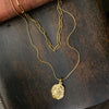 Gold necklace with 2 chains, the longer chain has a gold pendant on it, the shorter chain is a slightly chukier gold link