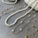Pearl and gold chain necklaces on a textured surface