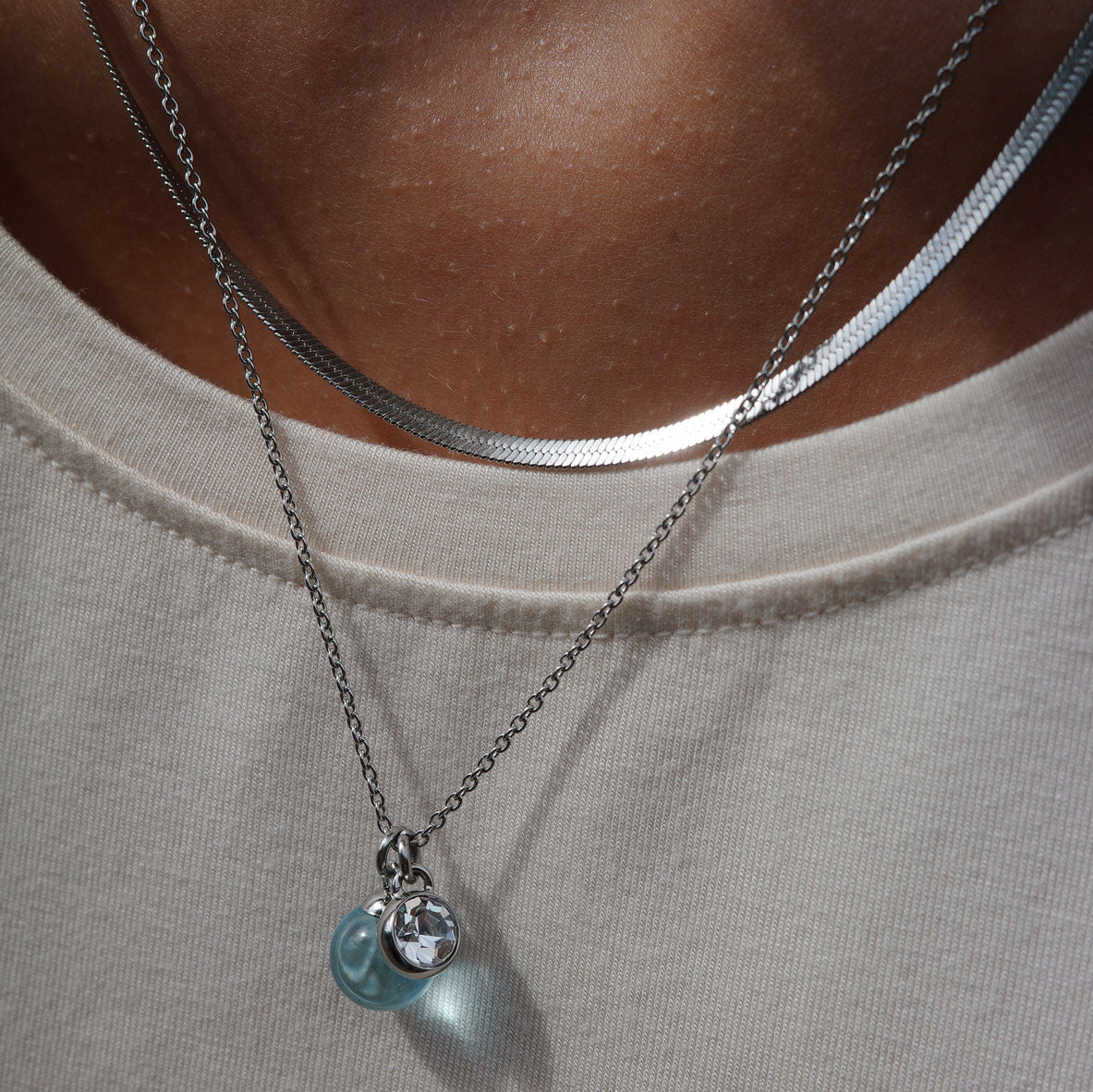 Silver necklace with blue glass and crystal pendants on model