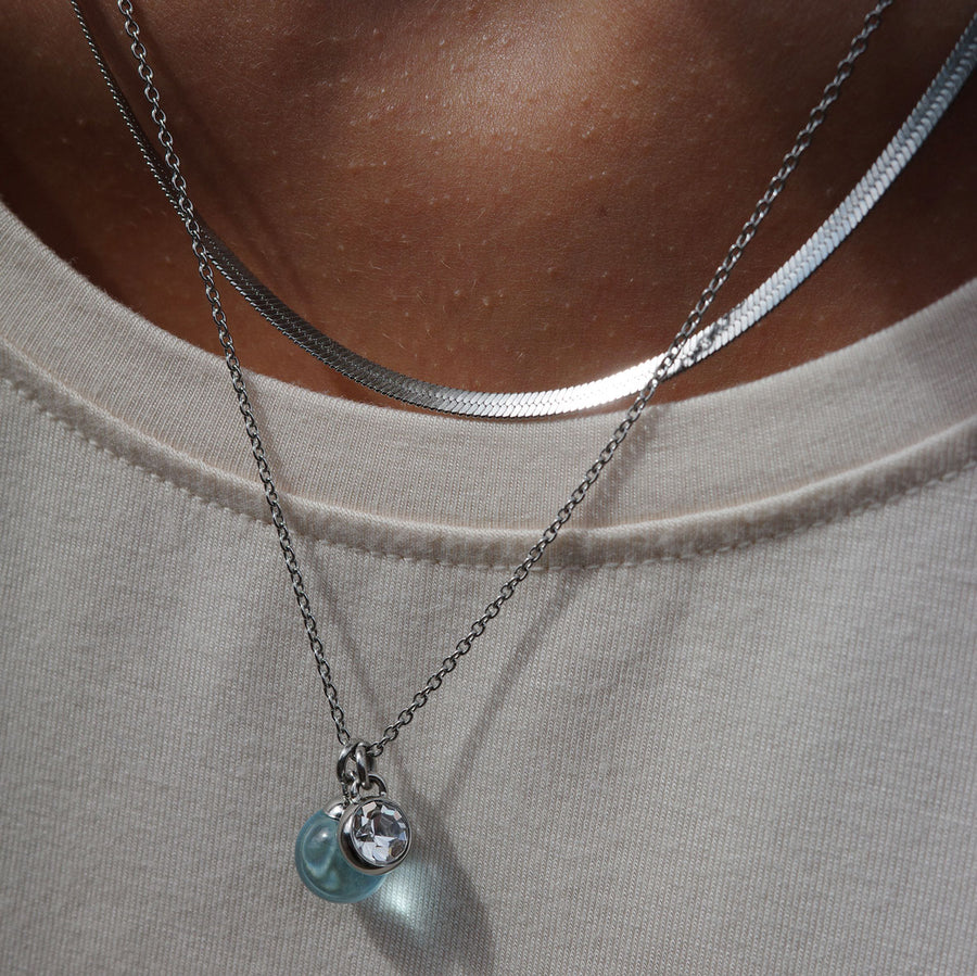Silver necklace with blue glass and crystal pendants on model