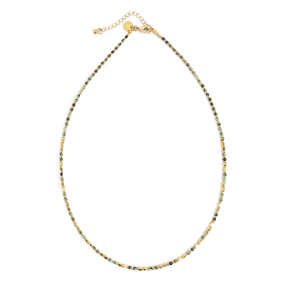 Necklace with small gold and green beads on a white background
