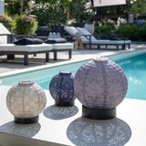 Group of three round lamps in purple and taupe sheds beside a pool on lumiz lamp stands
