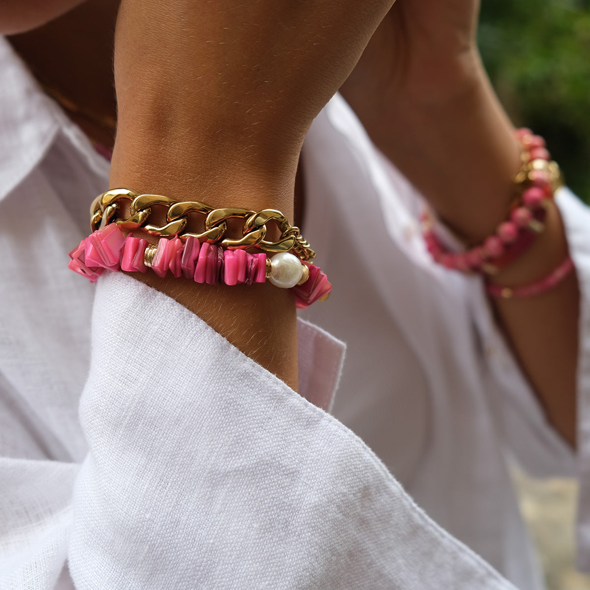 Gold chain bracelet and  pink shell on a wrist against a white backgroundracelet 