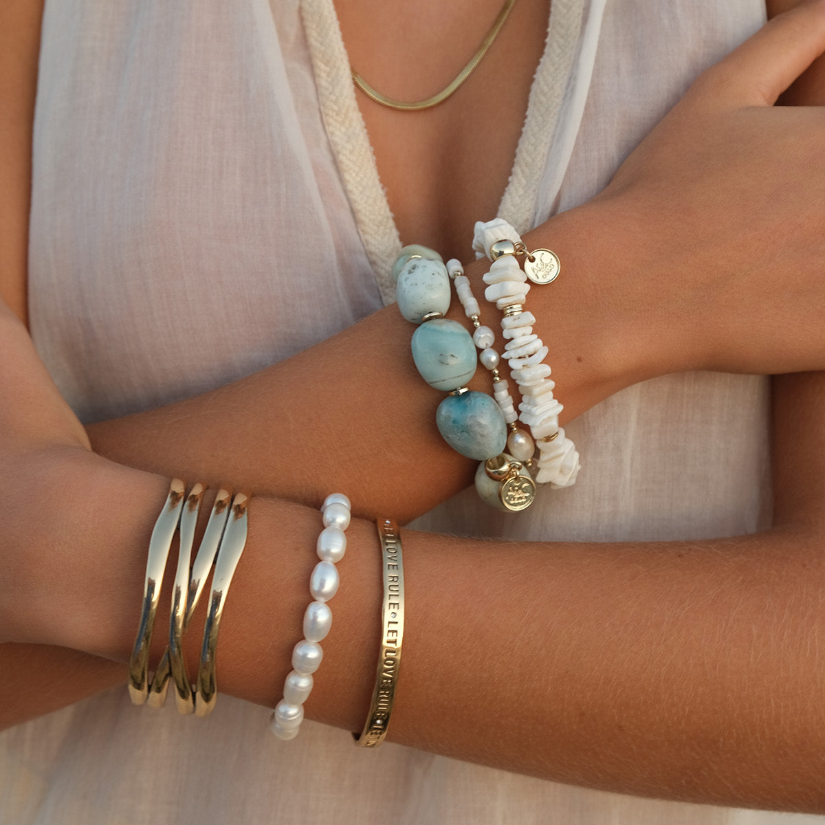Close-up of a person's arm wearing multiple bracelets with beads and gold bands.