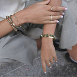 Close-up of hands with bracelets and rings on a blurred background