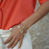 Person wearing a colorful bracelet with charms on a blurred background