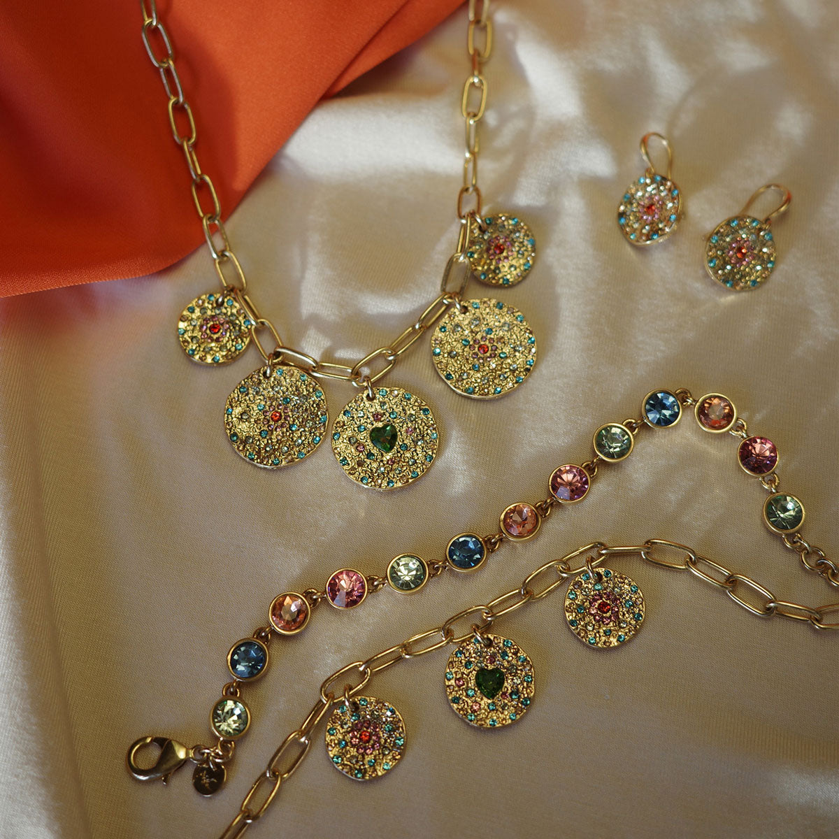 Gold coloured vbrance collection of jewellery showing necklace, bracelet and earrings all with colourful stones 