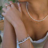 Close-up of a person wearing pearl necklaces and bracelets with a blurred background