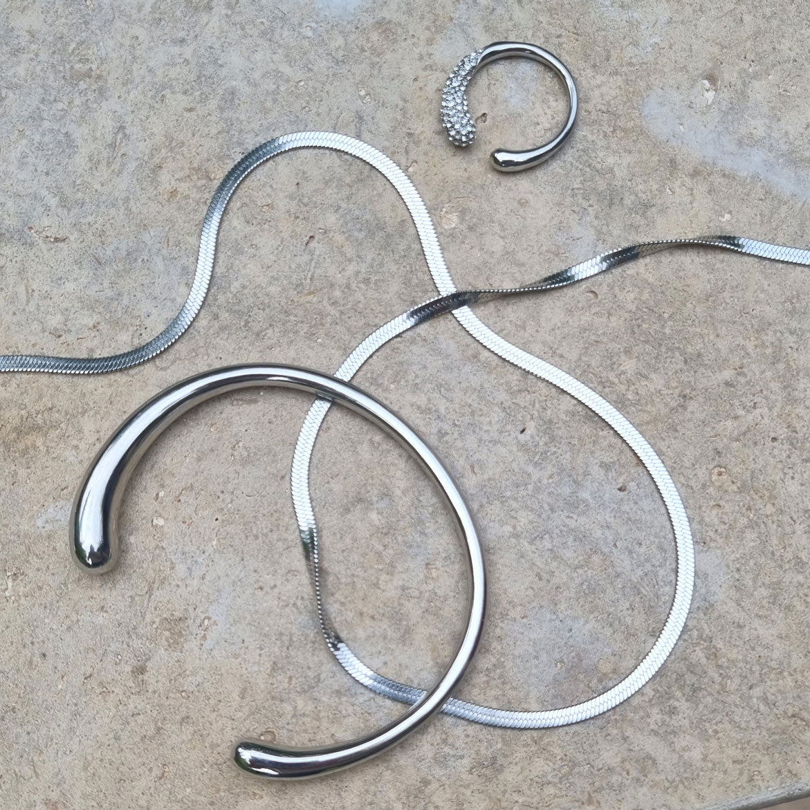 Silver necklaces, bracelet and earrings on a textured surface