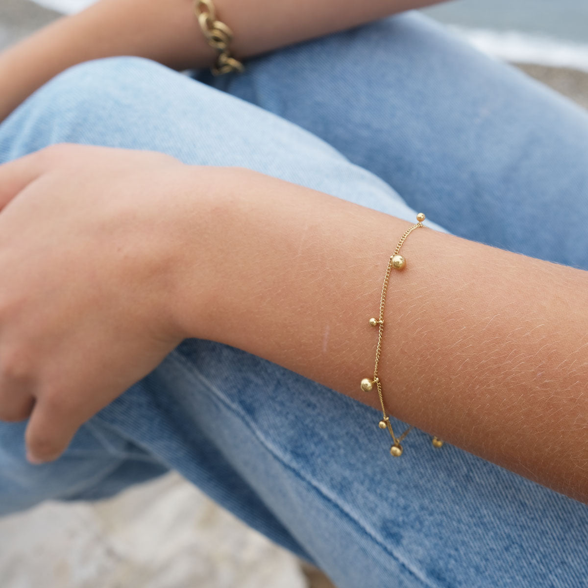 Gold bracelet on a person's wrist with a blurred background