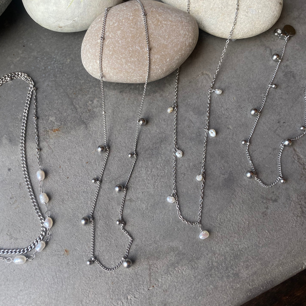 Silver necklaces  and bracelets with beads on a stone surface