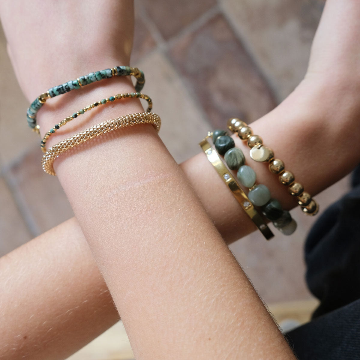 Close-up of a wrist wearing multiple bracelets with a blurred background