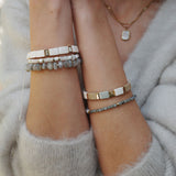 Model wearing a collection of bracelets from A&C Oslo including the enamel tiles bracelet in slated linen colour at Cerise NZ.