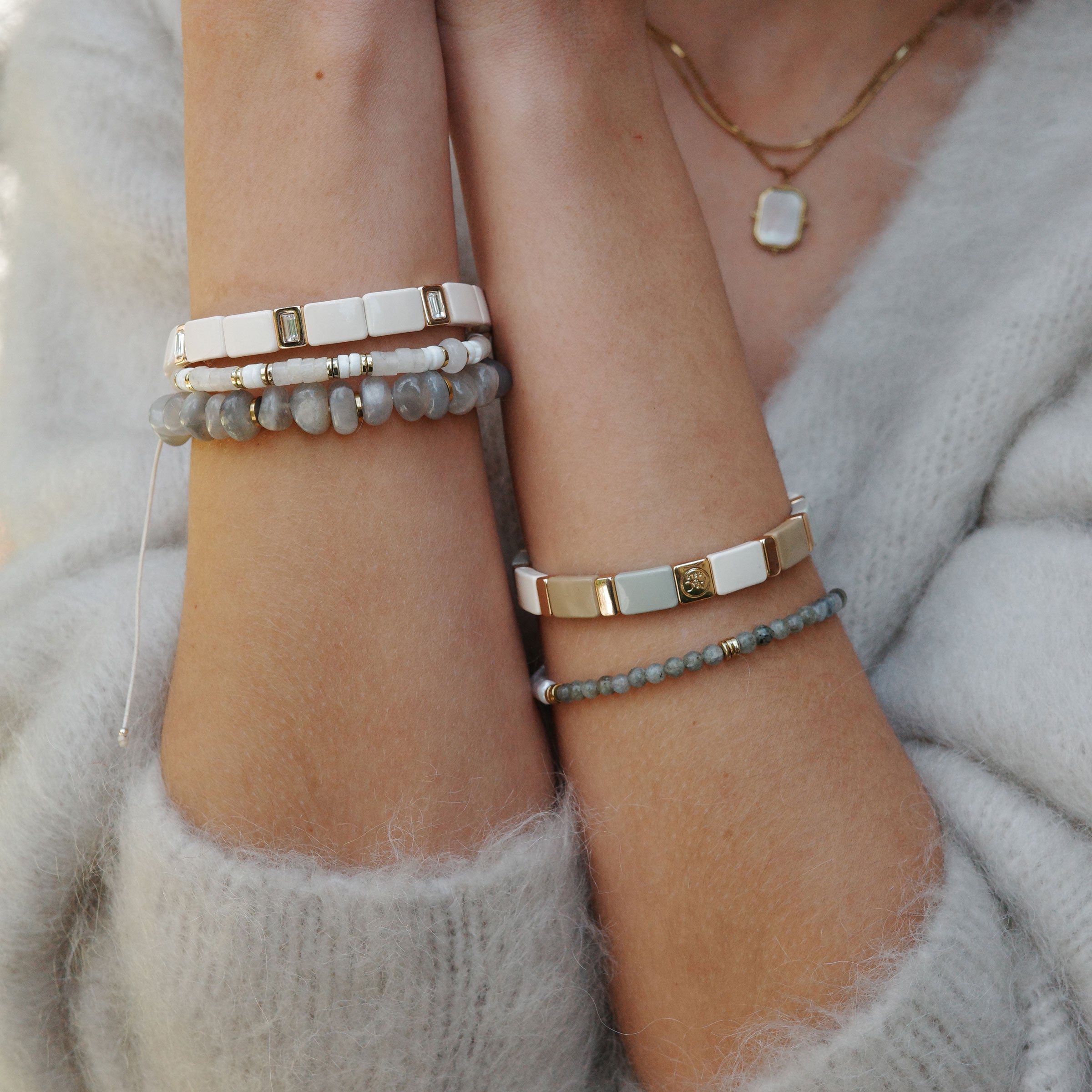 Model wearing a collection of bracelets from A&C Oslo including the enamel tiles bracelet in slated linen colour at Cerise NZ.