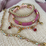A&C Oslo Multi Stone bacelet from the Sweet Droplets collection, featuring beautiful soft multi coloured crystals and 14K gold plate beads. Shown here with a pink enamel tiles bracelet, the gorgeous new corded bracelet and colourful pink & green friendship bracelet at Cerise NZ.